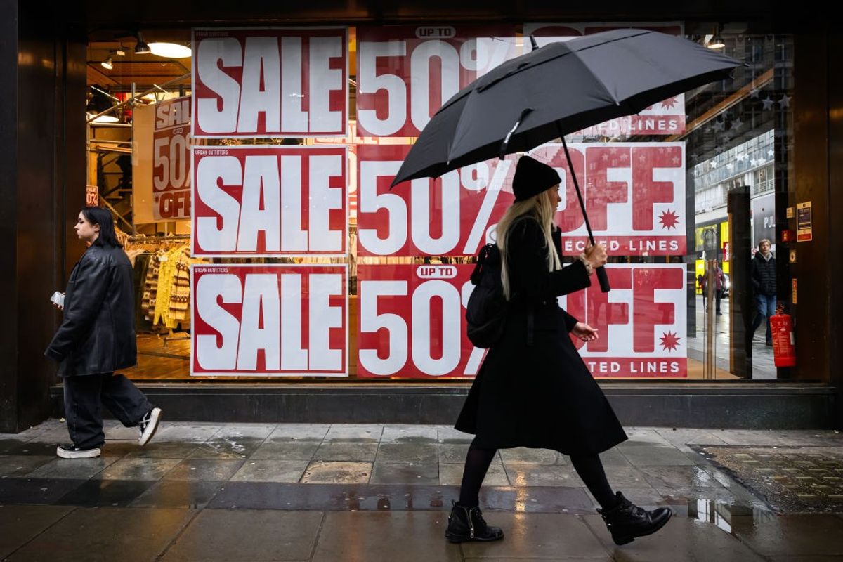 A woman walks past a window display promoting an ongoing sale