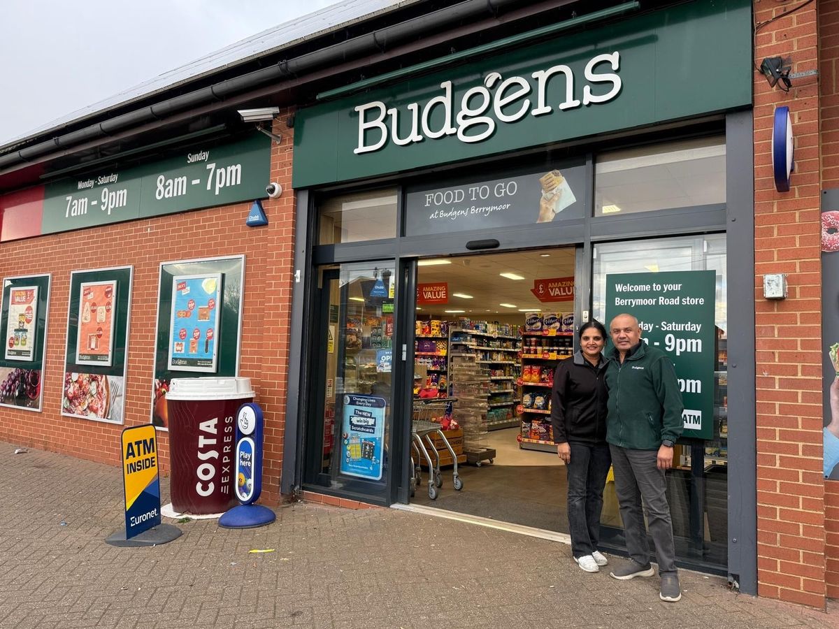 Budgens Berrymoor storefront in Wellingborough with Costa Express machine, ATM, and owners standing outside