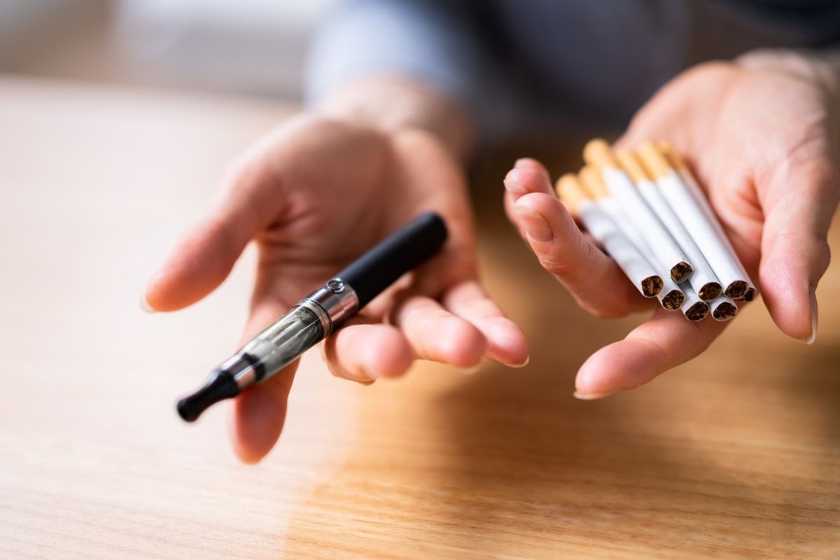 Woman Holding Vape And Tobacco Cigarettes